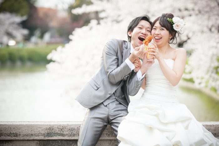 桜がキレイな名城公園の橋に座ってからあげを食べる夫婦