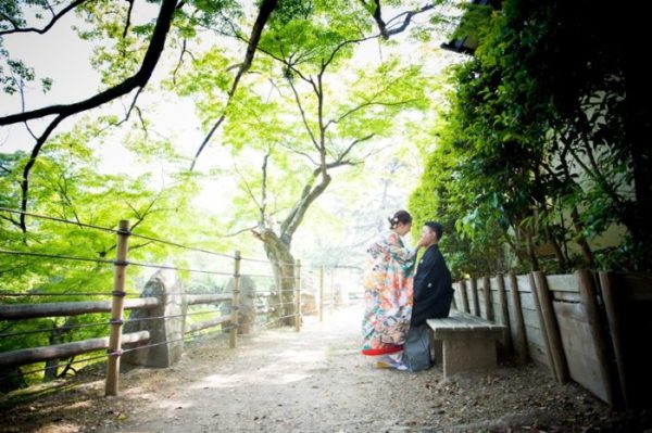 岡崎城の公園で緑のキレイなスポットのベンチに座って笑顔で見つめ合うふたり