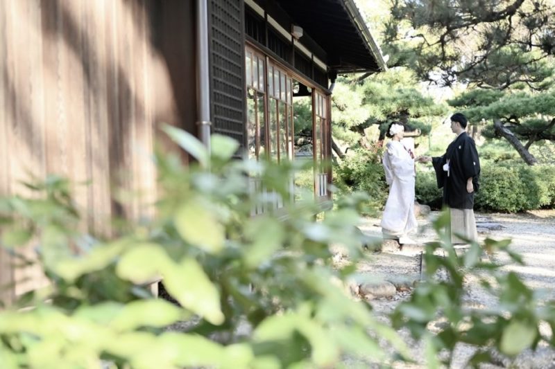 白い色打掛を着た新婦と黒い紋付を着た新郎のお庭での和装ショット
